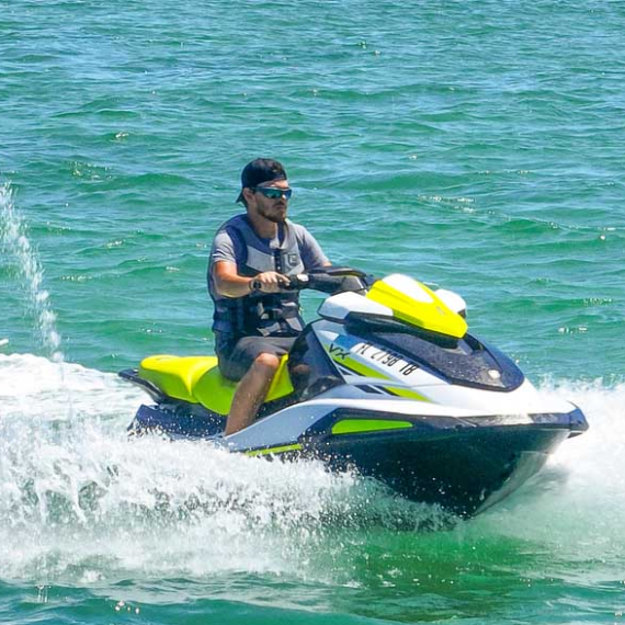 Person riding a jet ski on clear blue water with waves.