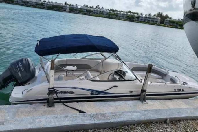Small motorized boat docked beside a stone edge on calm water.